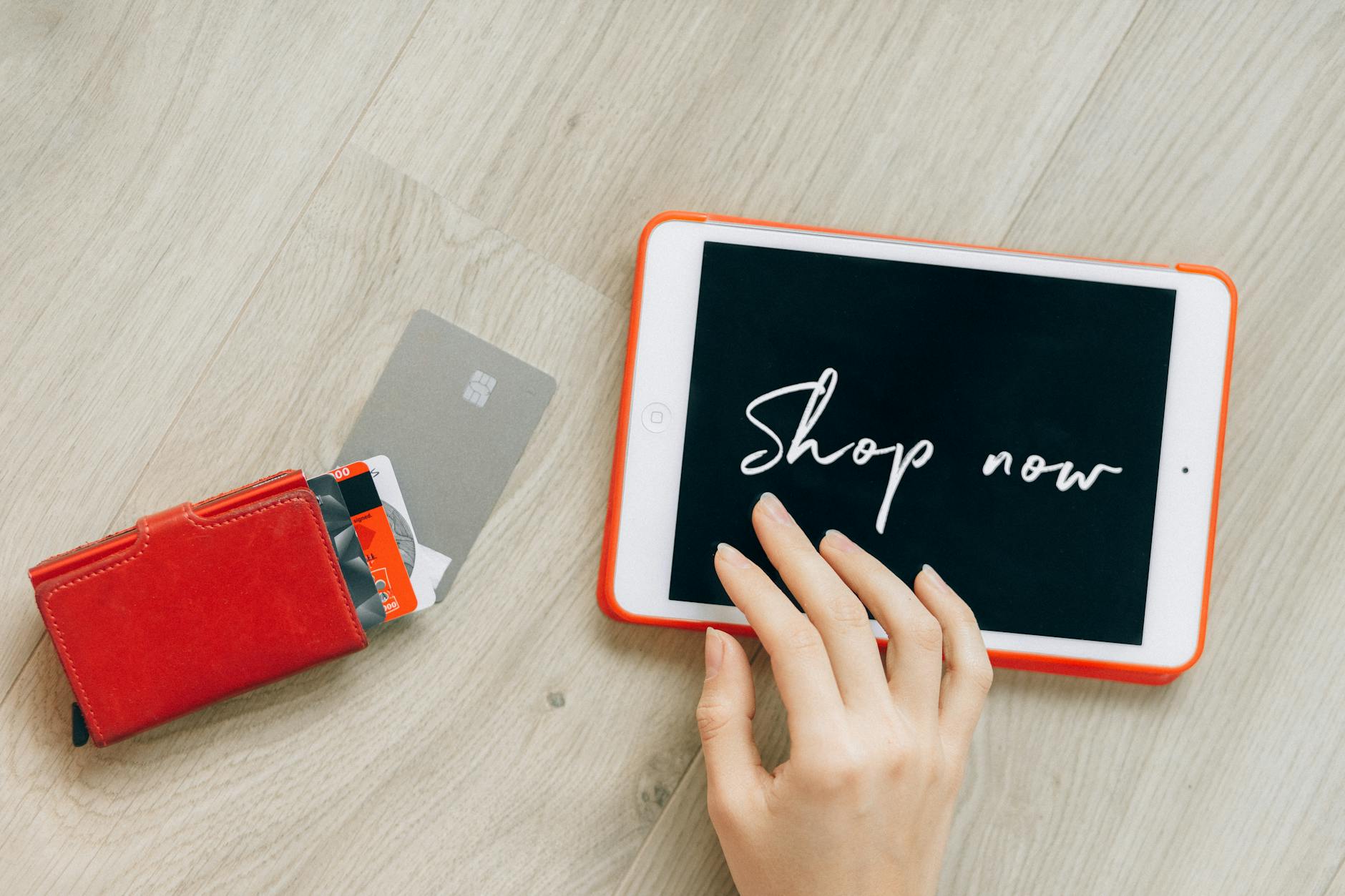 Multiple credit cards fanned out next to a leather wallet on a wooden surface