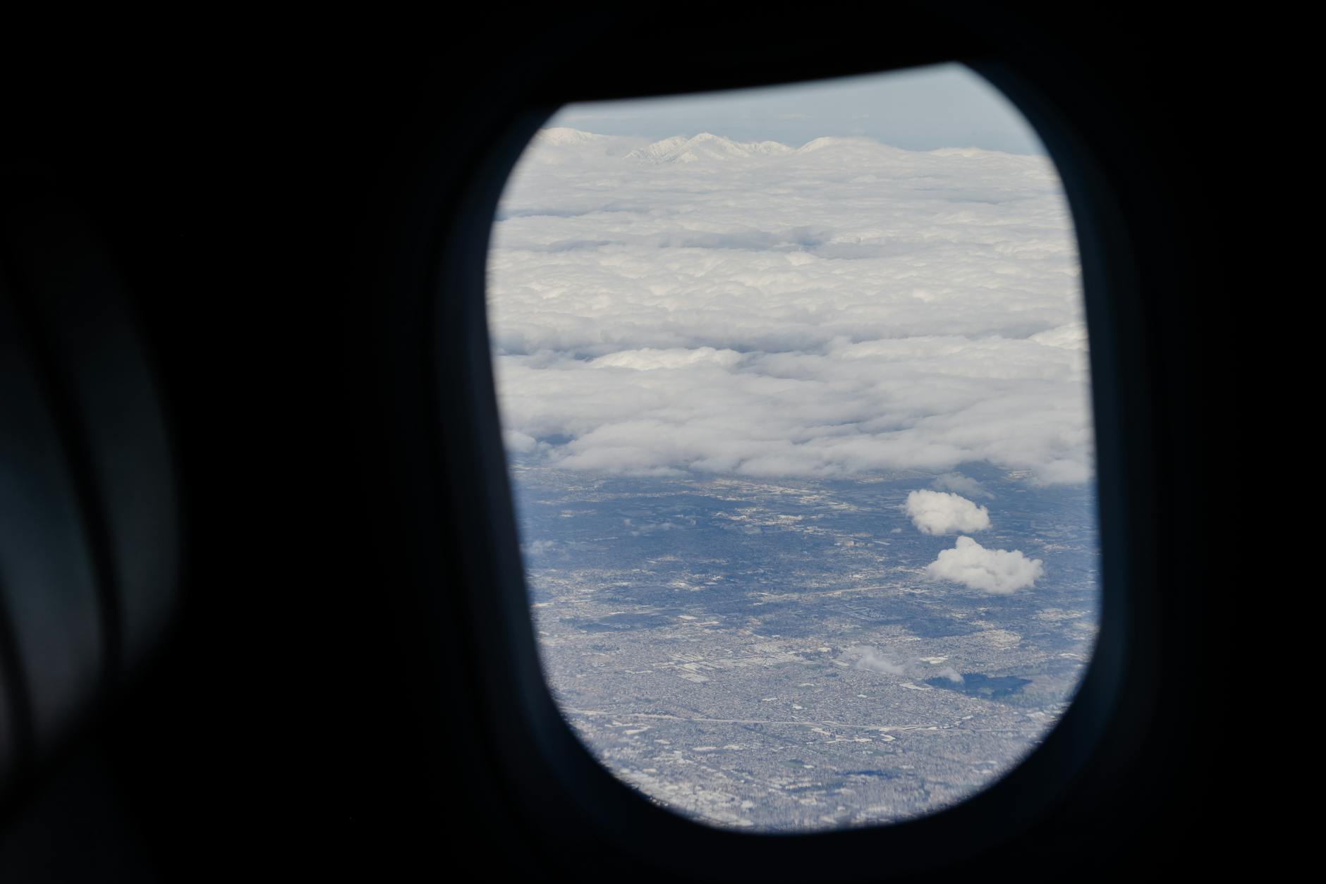 Airplane passenger looking out window at bright sky during flight