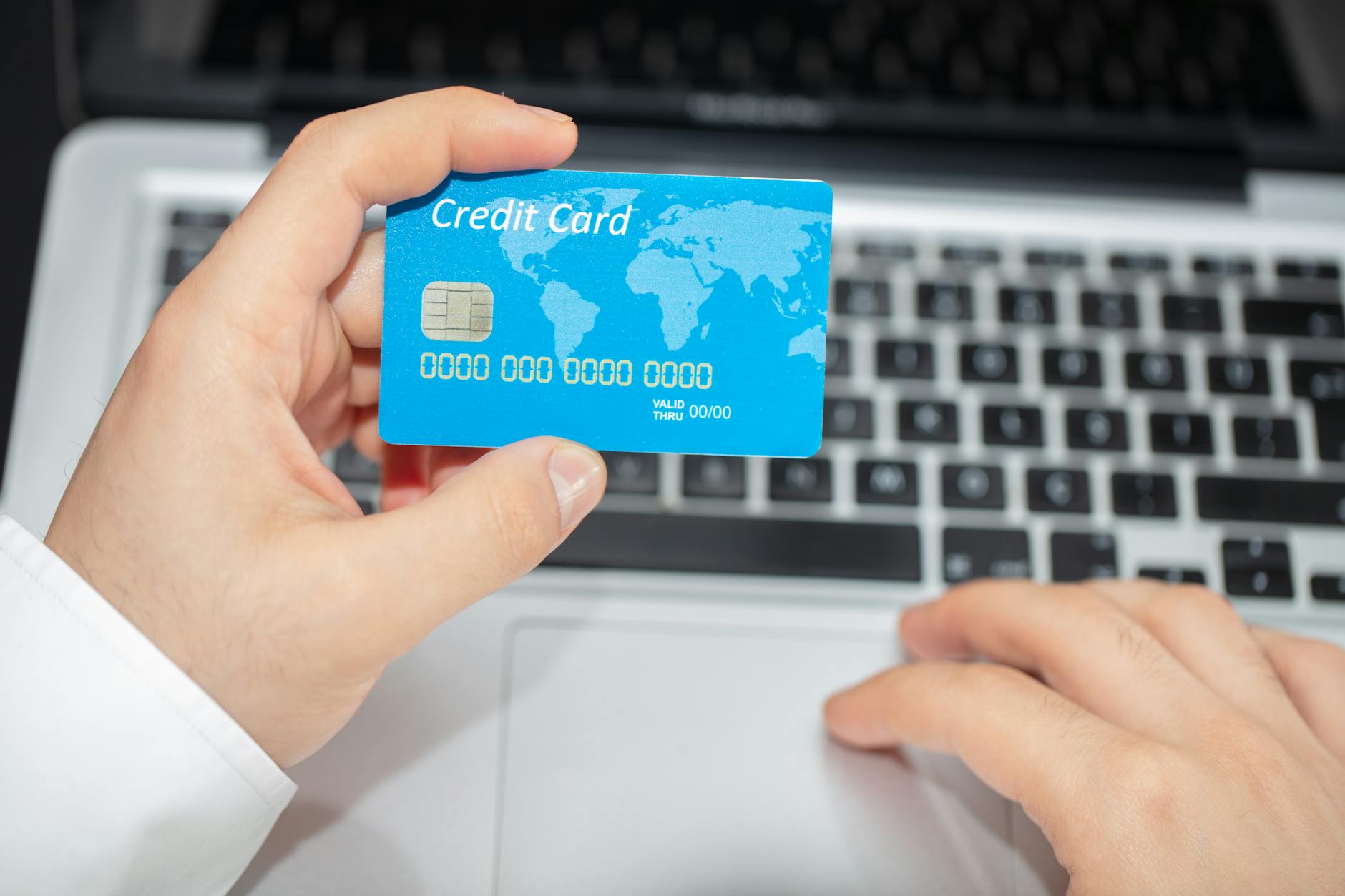Credit cards next to laptop showing travel booking website for points optimization