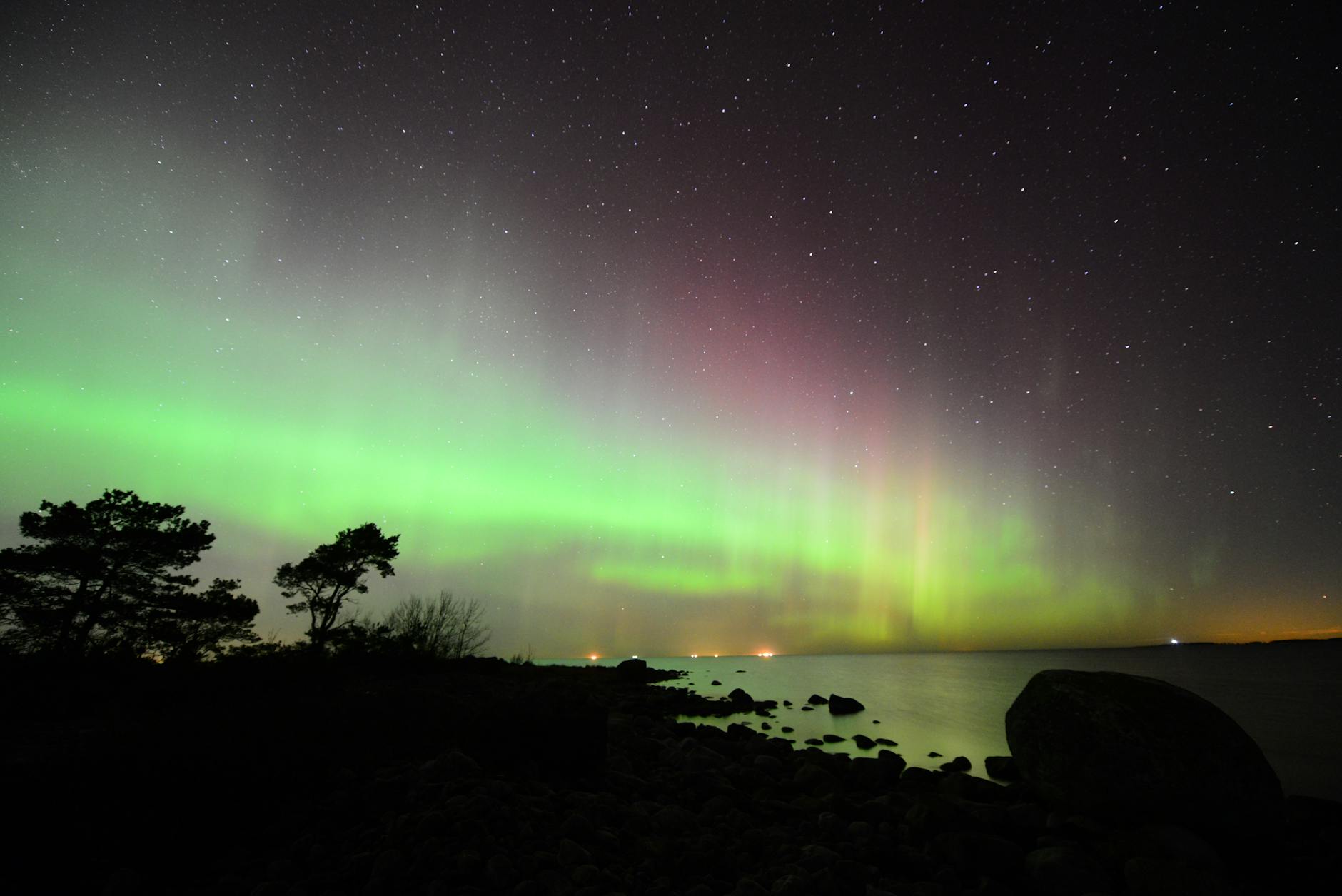 Aurora borealis dancing across dark winter sky with mountain silhouettes