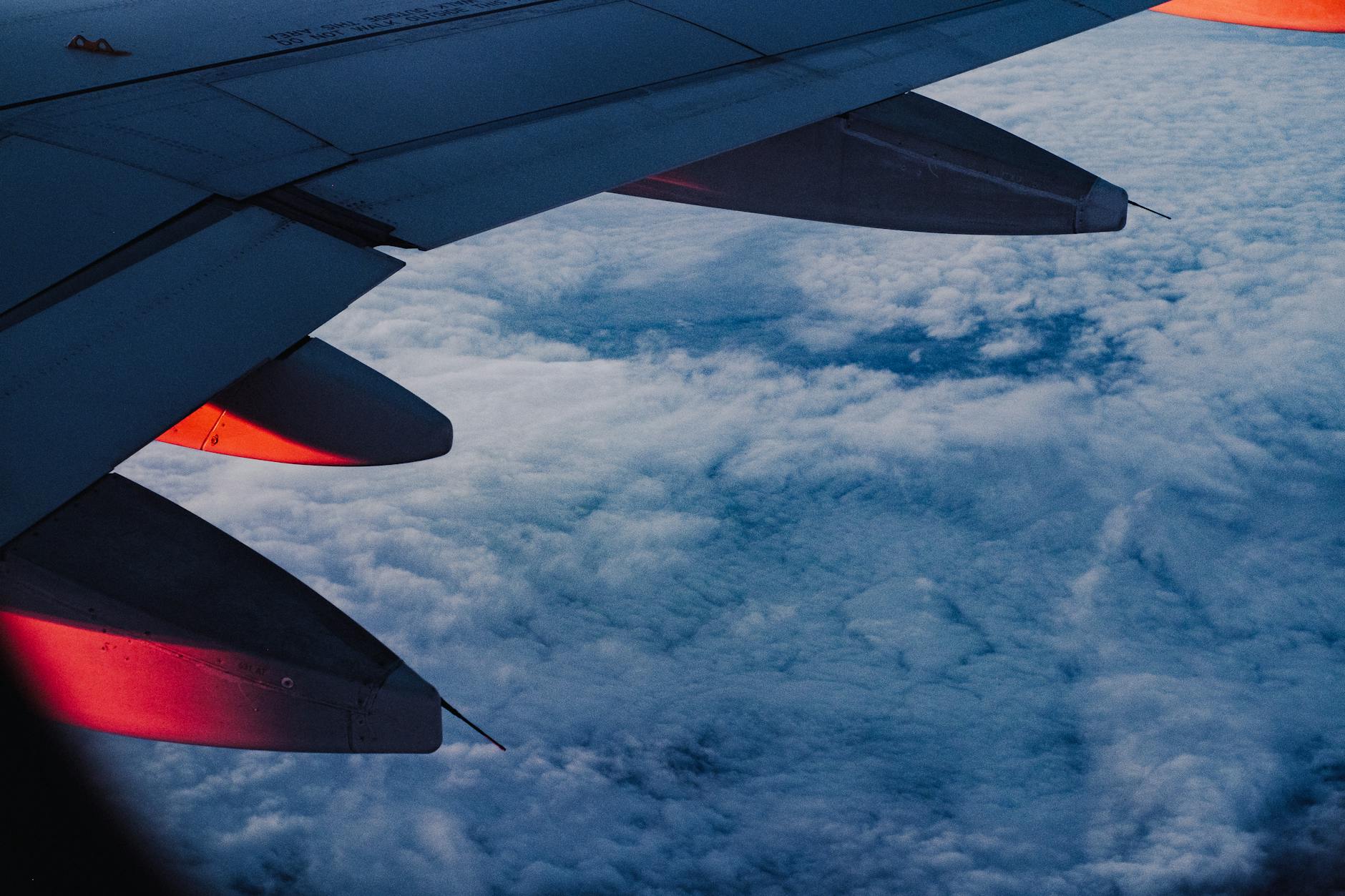 View of airplane wing above clouds during international flight