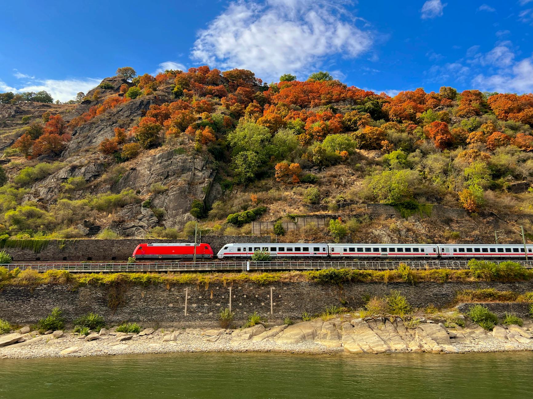 Scenic train traveling through European countryside with mountains and green landscapes