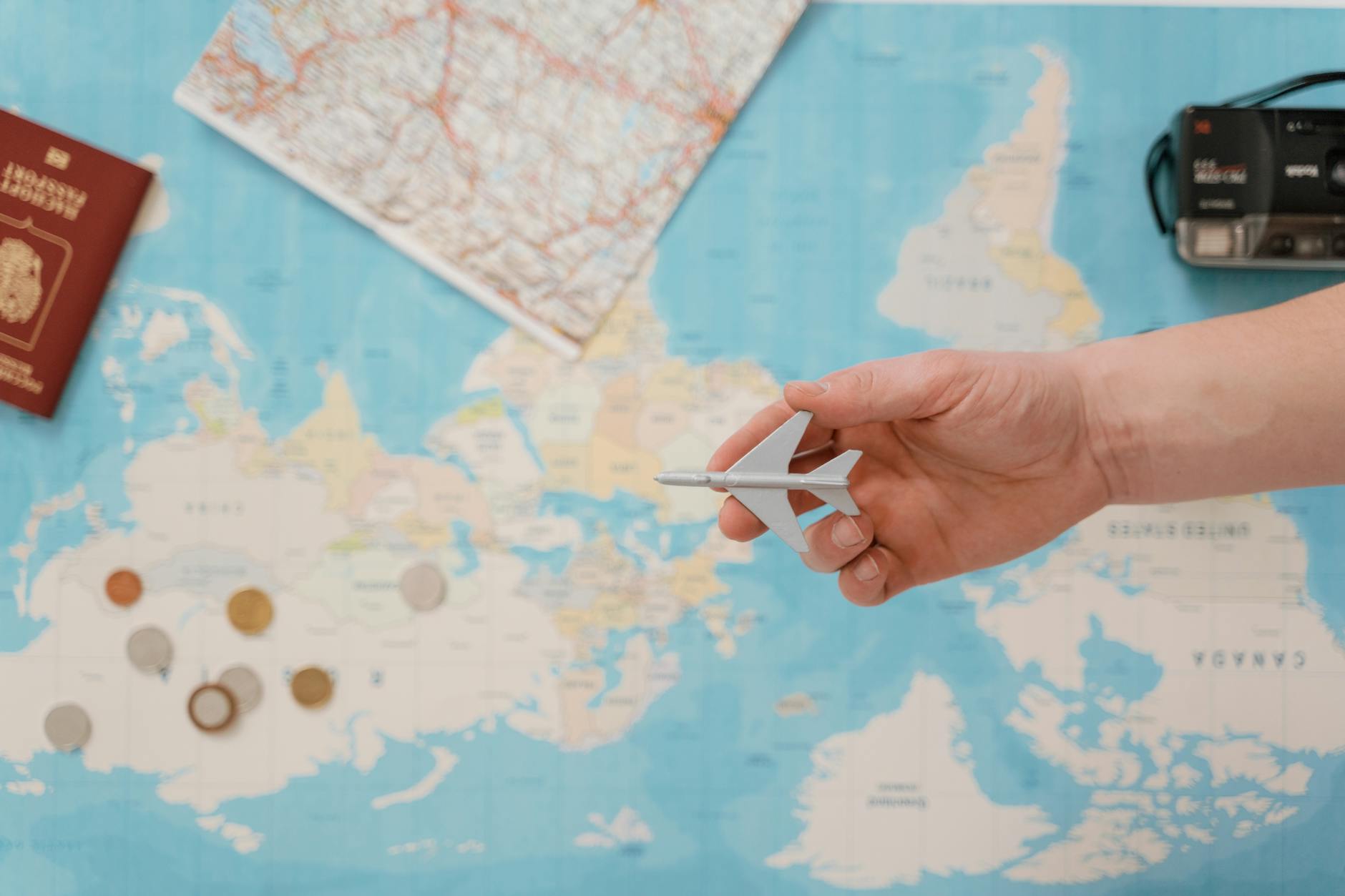 World map with travel planning materials including passport and airline tickets