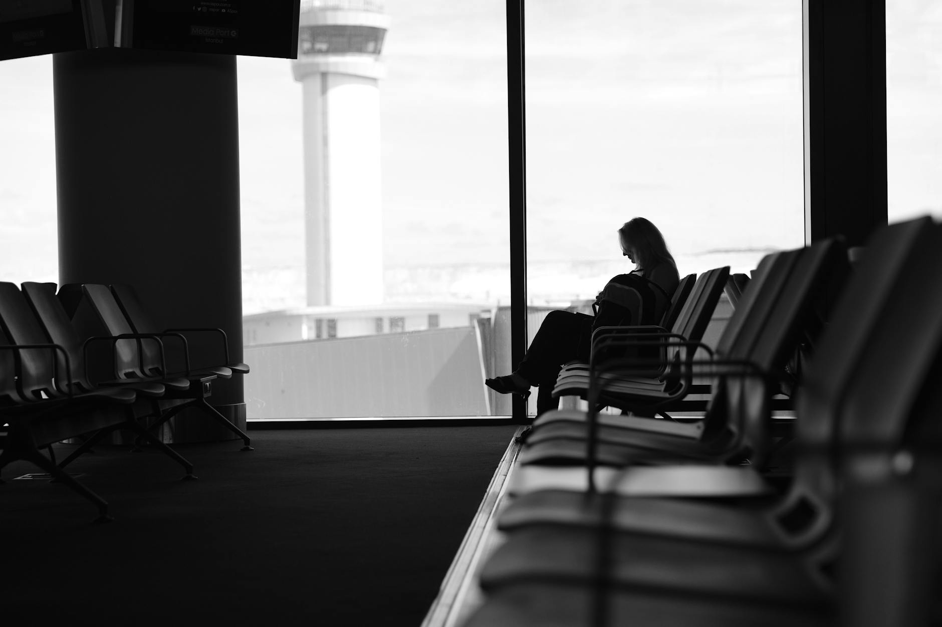 Modern airport business lounge interior with comfortable seating and city views through large windows