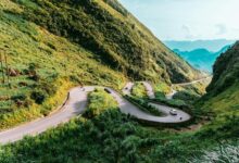 A winding mountain road cutting through dramatic limestone karst landscape in northern Vietnam