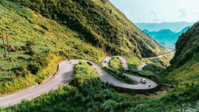 A winding mountain road cutting through dramatic limestone karst landscape in northern Vietnam