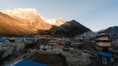 Wide view of a dry high-altitude landscape in Nepal with rocky cliffs and distant Himalayan peaks