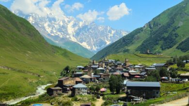 Stone medieval towers rising above a mountain village in the Svaneti region of Georgia with snow-capped peaks behind