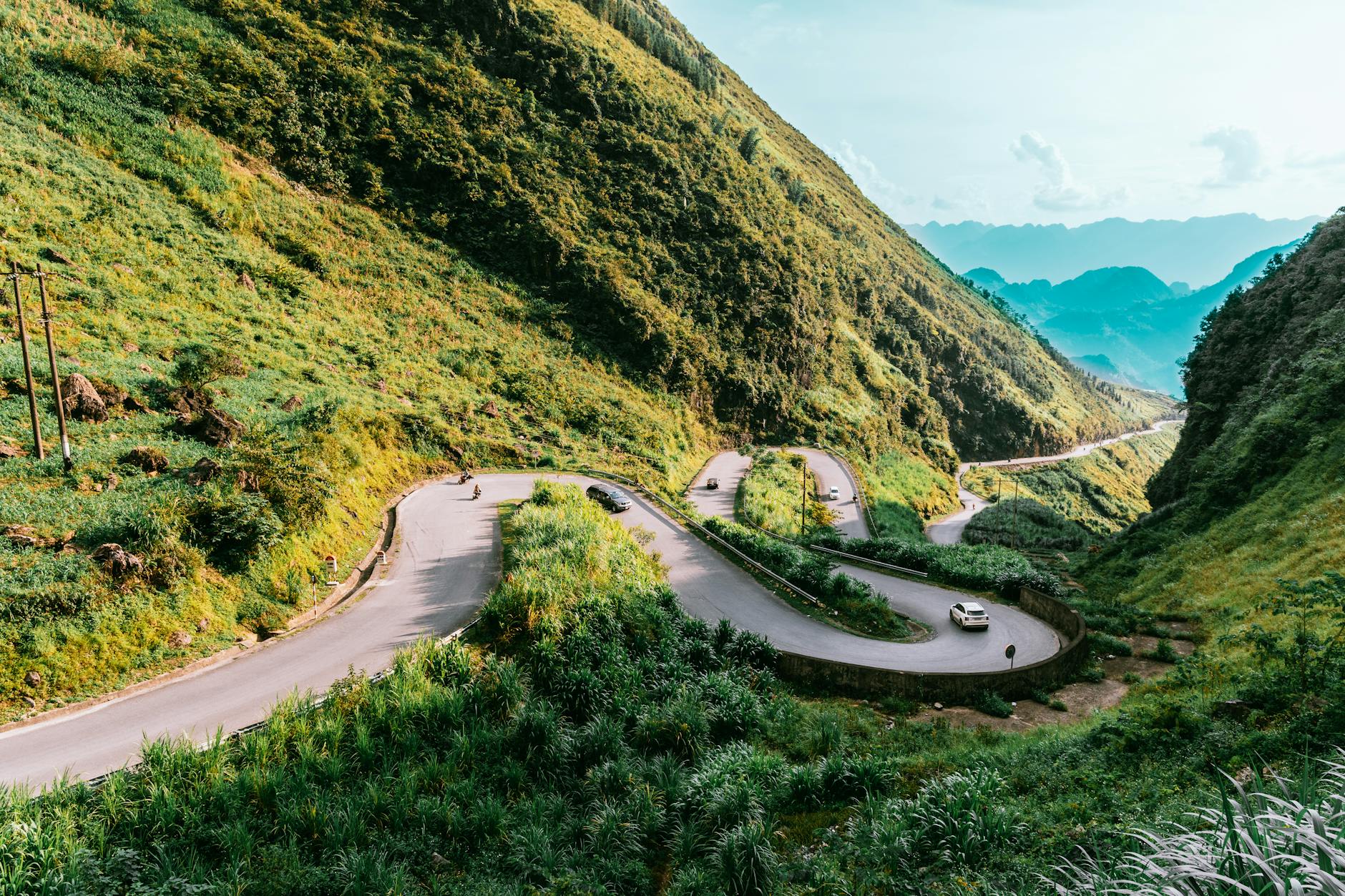 A winding mountain road cutting through dramatic limestone karst landscape in northern Vietnam