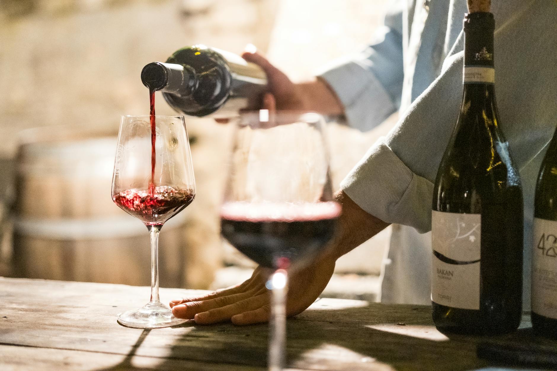Guests tasting wine at an outdoor terrace overlooking vineyard hillsides