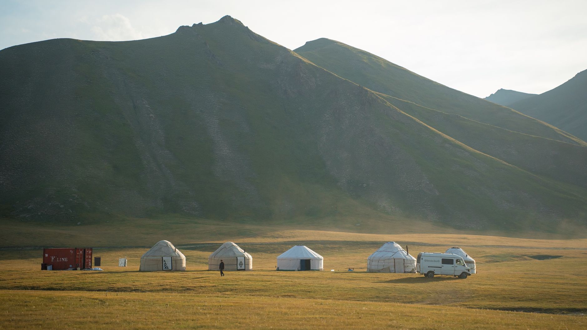 Traditional Kyrgyz yurt camp in an alpine meadow with mountain backdrop