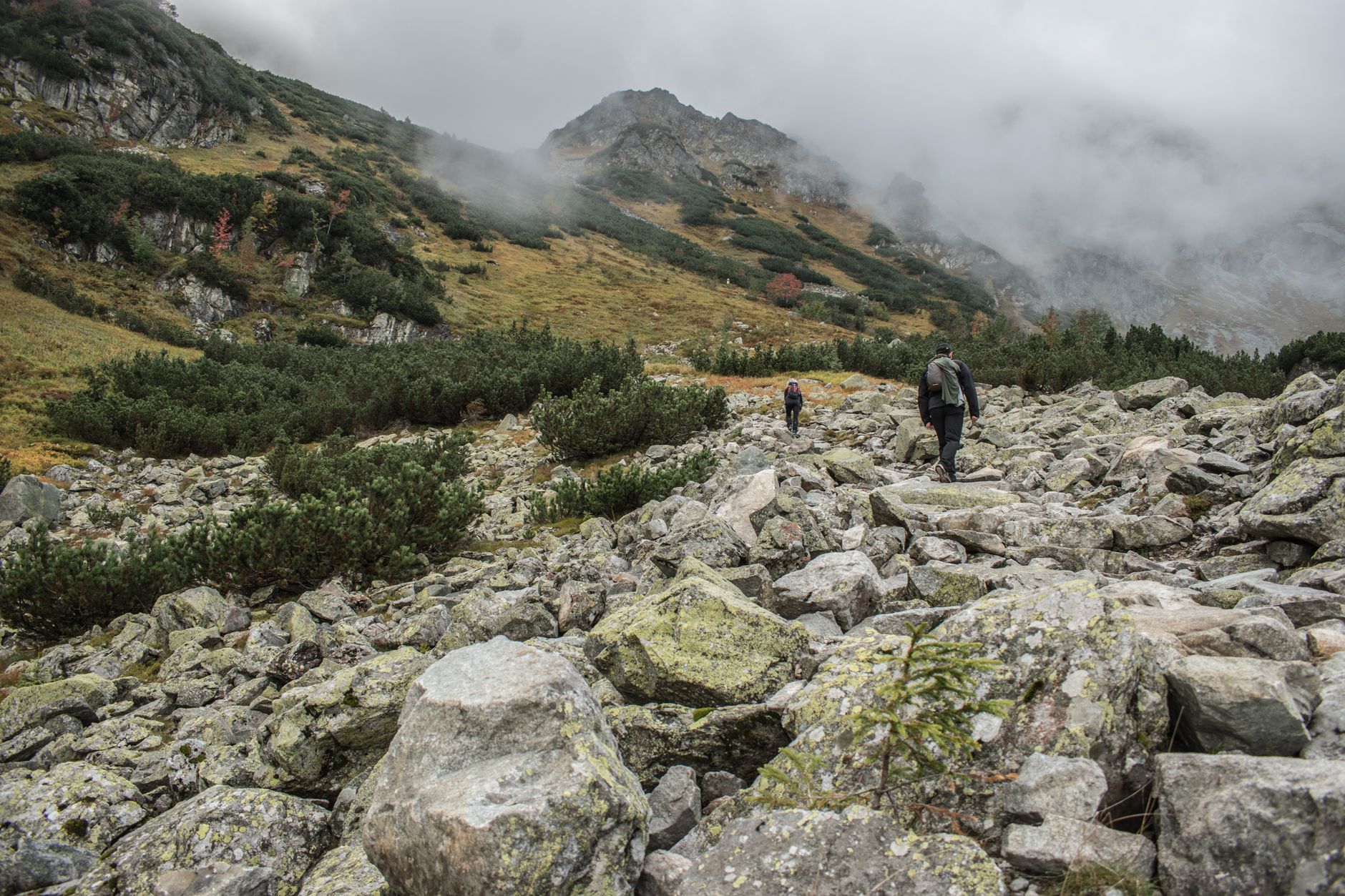 Hiker walking a narrow mountain trail with steep rock formations on either side