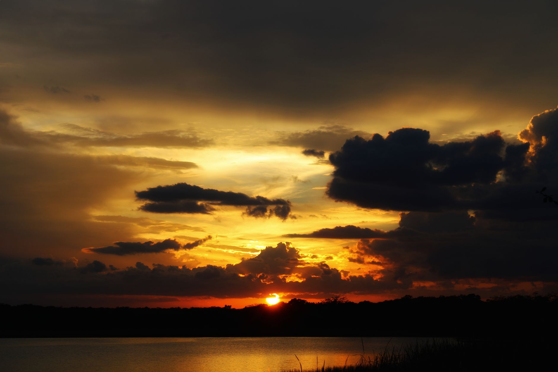 Wide view of a calm African lake at sunset with mountains visible in the distance