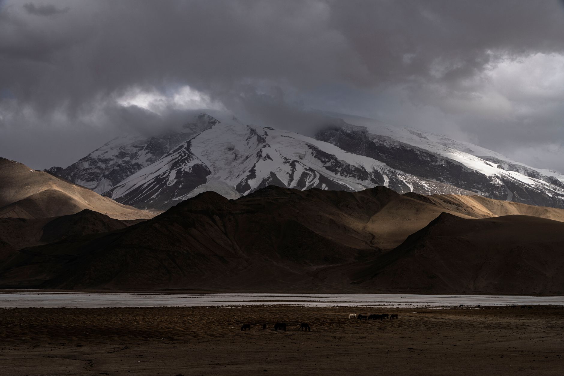 Remote mountain valley in the Pamir range with a river running through rugged terrain