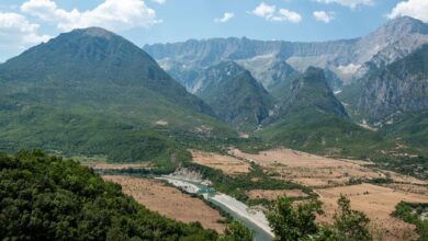 Wide view of a glacially carved alpine valley with turquoise river and forested peaks in the Albanian Alps