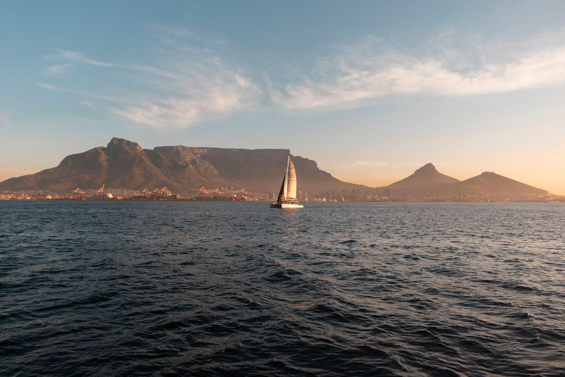 Small sailboat on a calm inland lake with mountainous shoreline in the background
