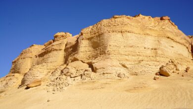 Wide red sandstone formations under clear blue sky in Wadi Rum desert landscape