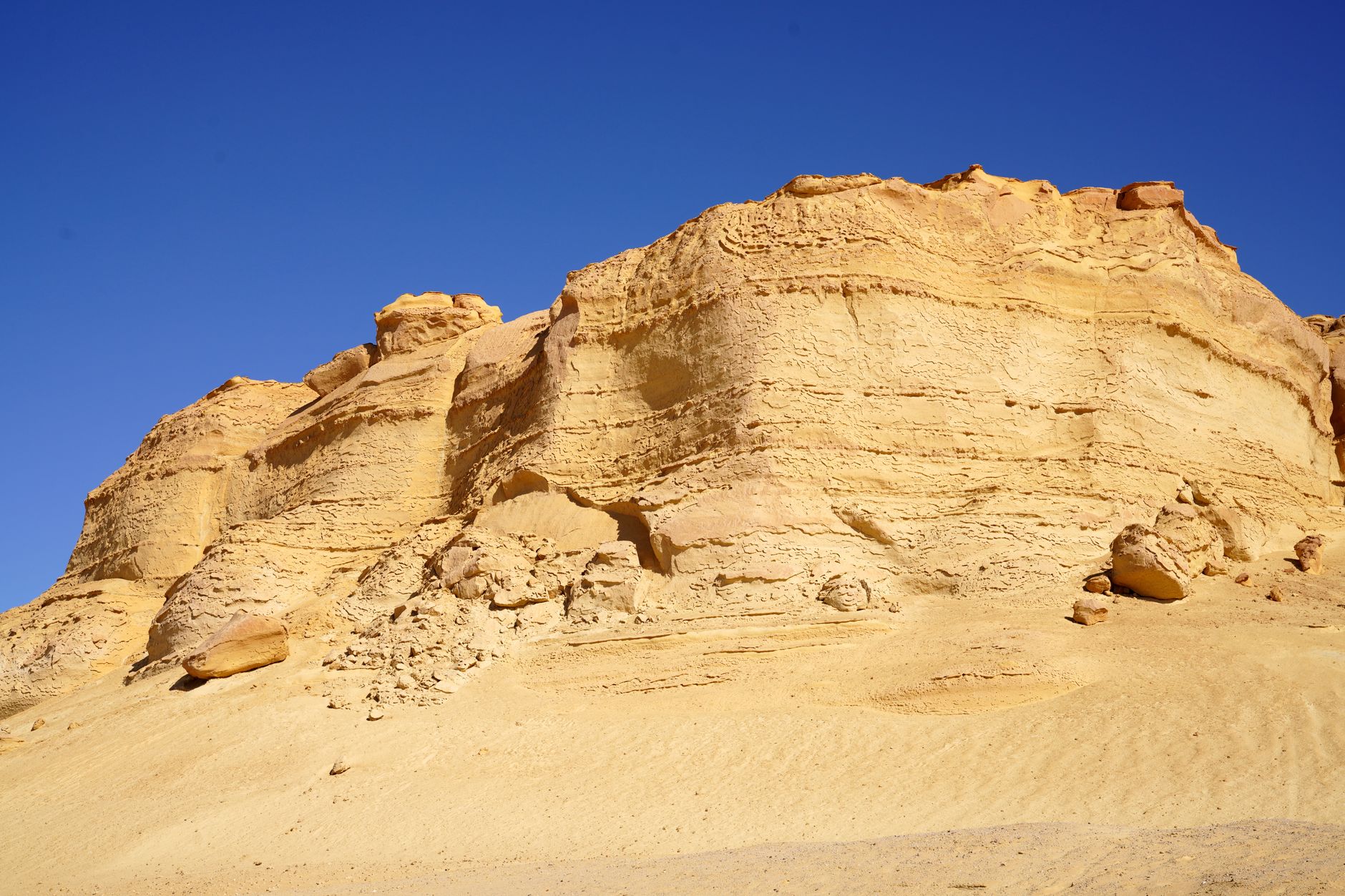 Wide red sandstone formations under clear blue sky in Wadi Rum desert landscape