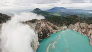Aerial view of a turquoise volcanic crater lake surrounded by steep Andean ridgelines