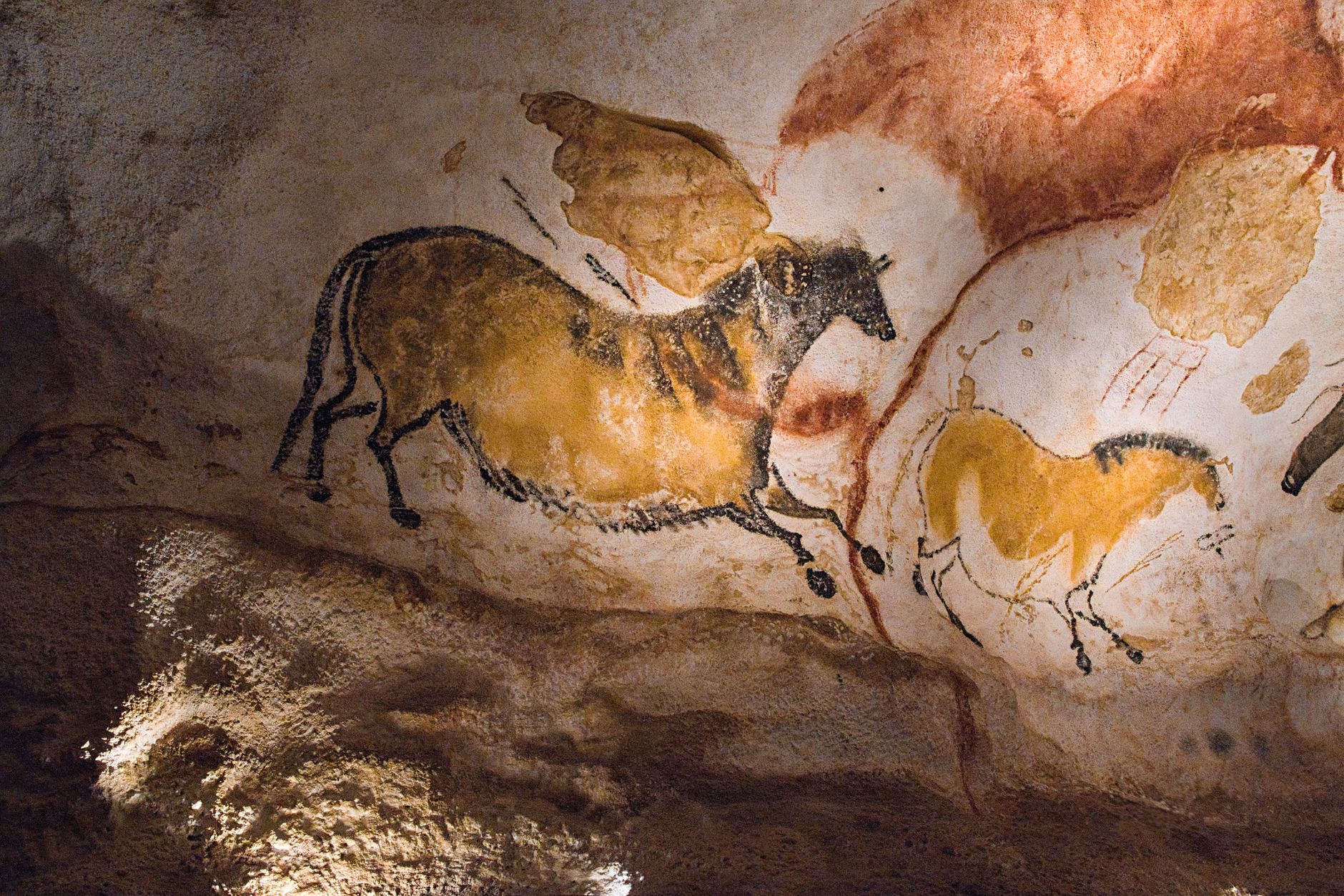 Prehistoric rock art paintings on a sandstone canyon wall showing human and animal figures