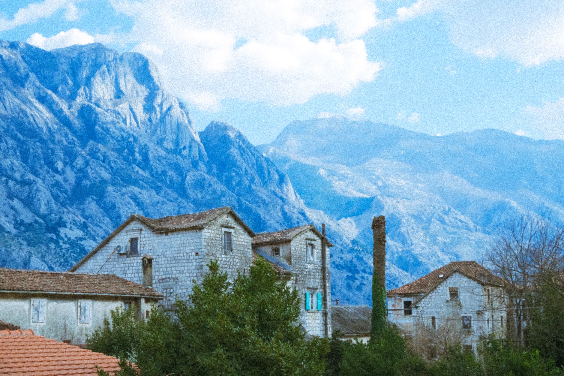 Traditional stone guesthouse in a remote mountain village surrounded by forested slopes