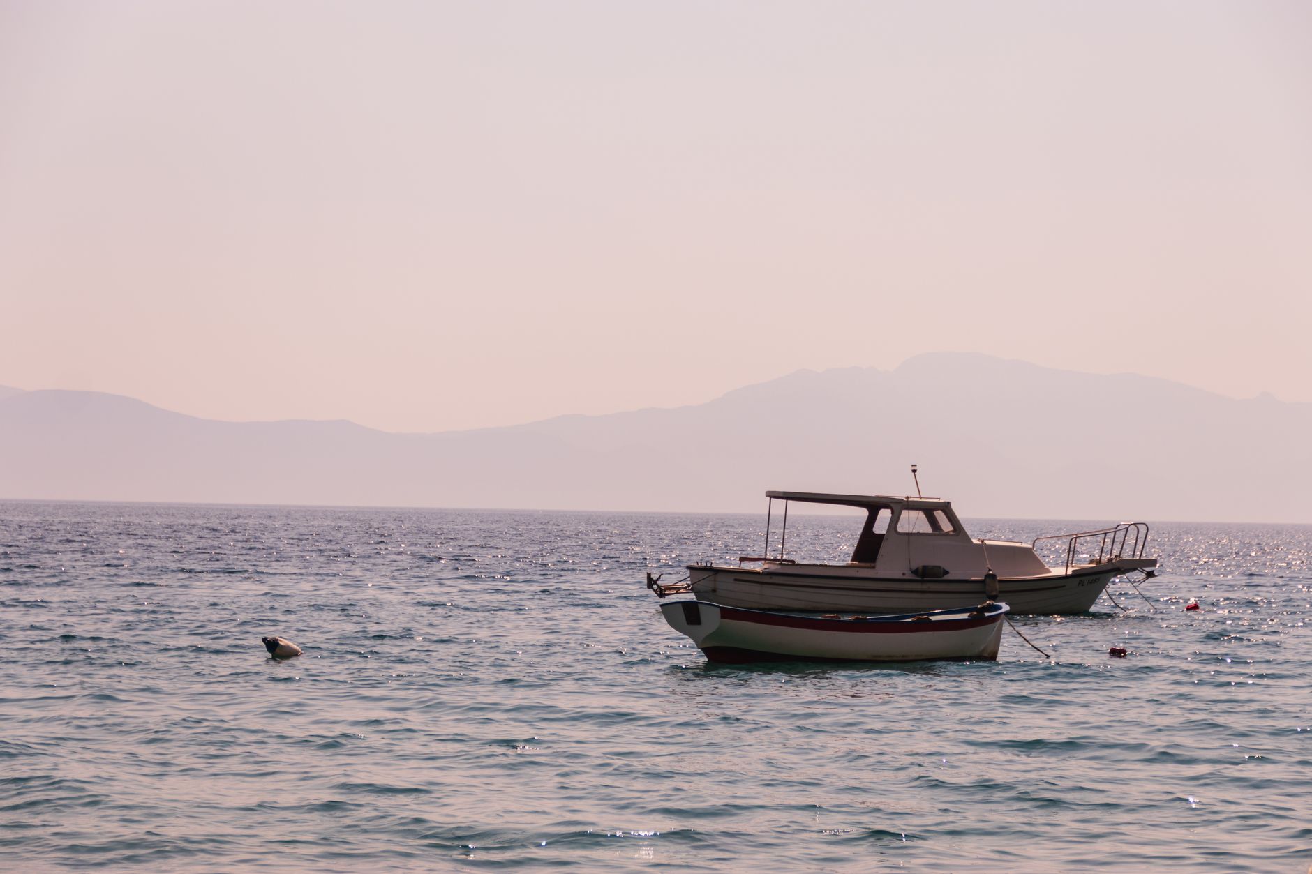 Small wooden fishing boats moored in a calm Mediterranean harbor at dawn