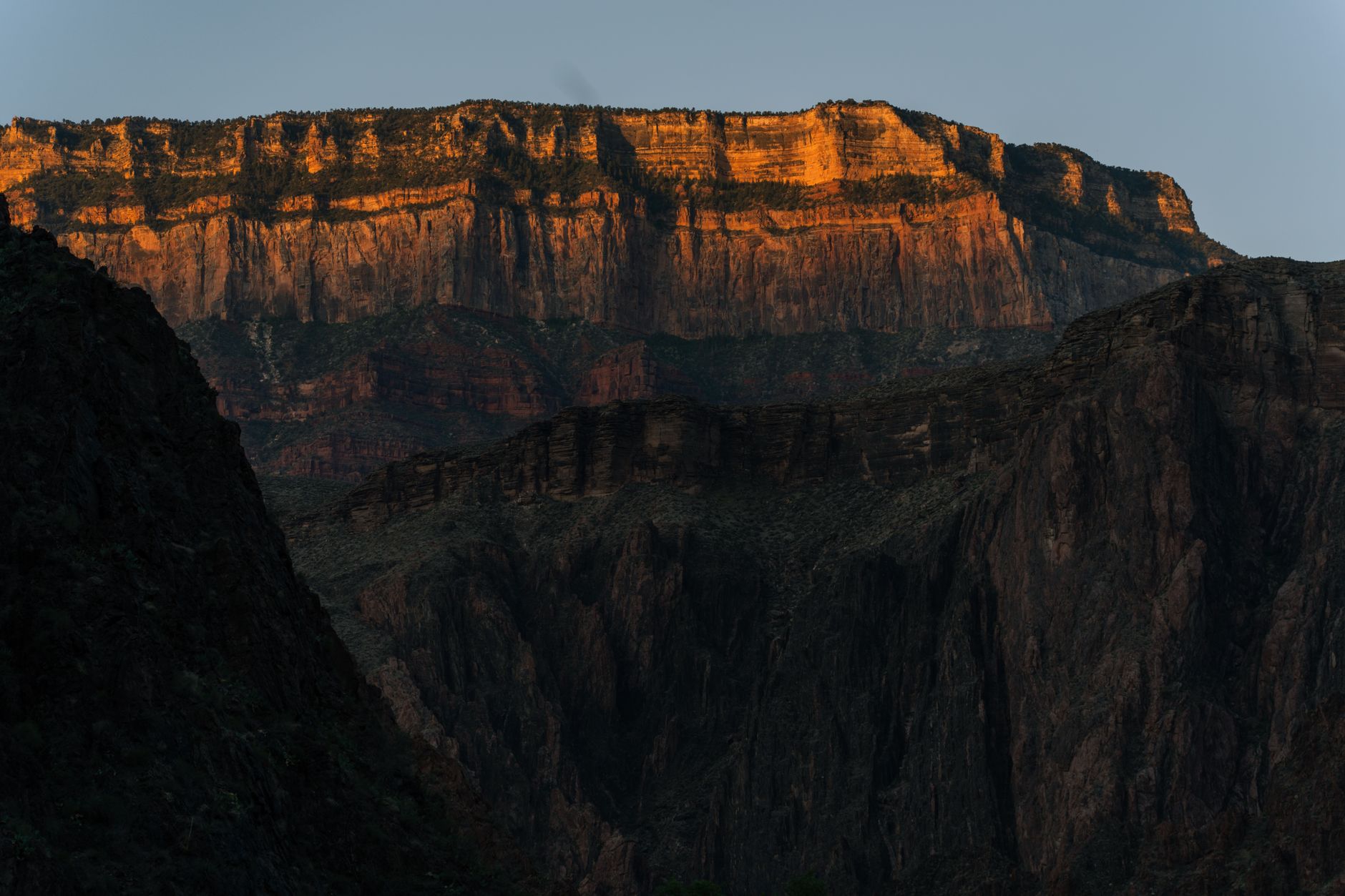 Sunrise light over a dramatic canyon rim with mist in the gorges below