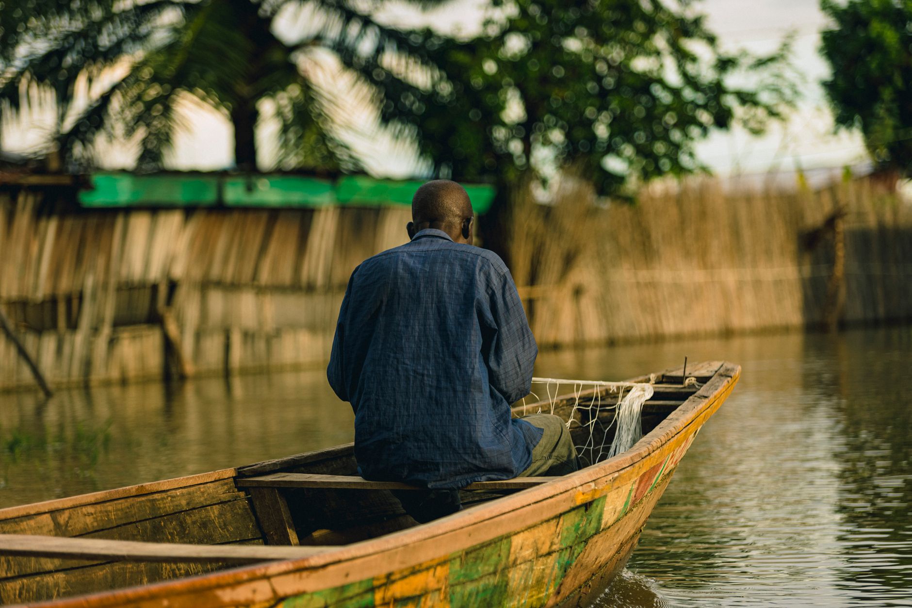 A wooden pirogue canoe on a calm river in West Africa surrounded by mangrove trees