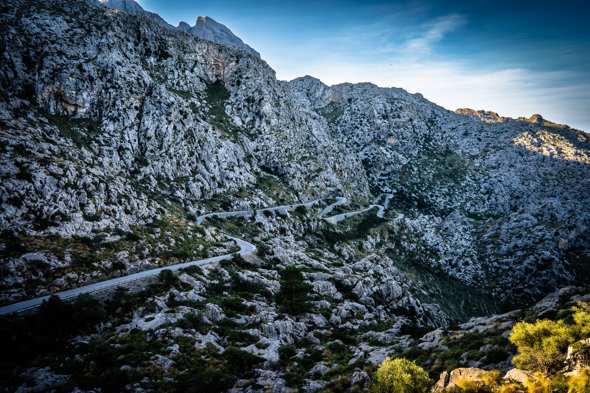 A winding gravel mountain road climbing steep switchbacks through highland terrain