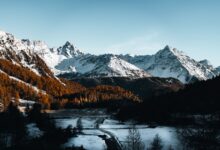 Snow-covered mountain valley in a high-altitude landscape with pine forests and clear winter skies