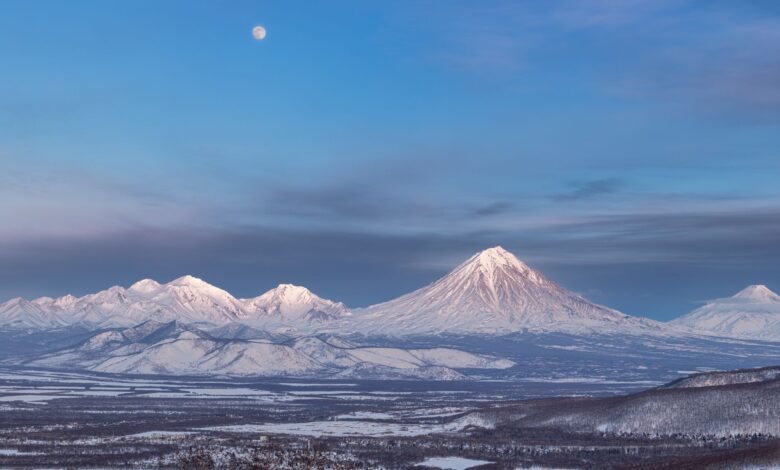 Snow-capped stratovolcano rising above an altiplano landscape at dawn