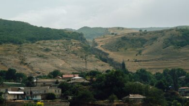 A remote village nestled in a narrow mountain canyon with red and orange rock walls