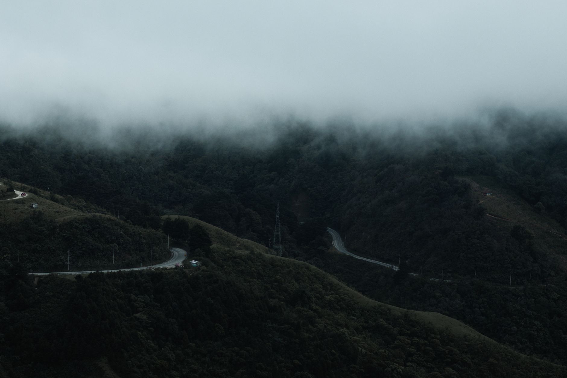 Winding mountain road descending through dense cloud forest in Bolivia's Yungas region
