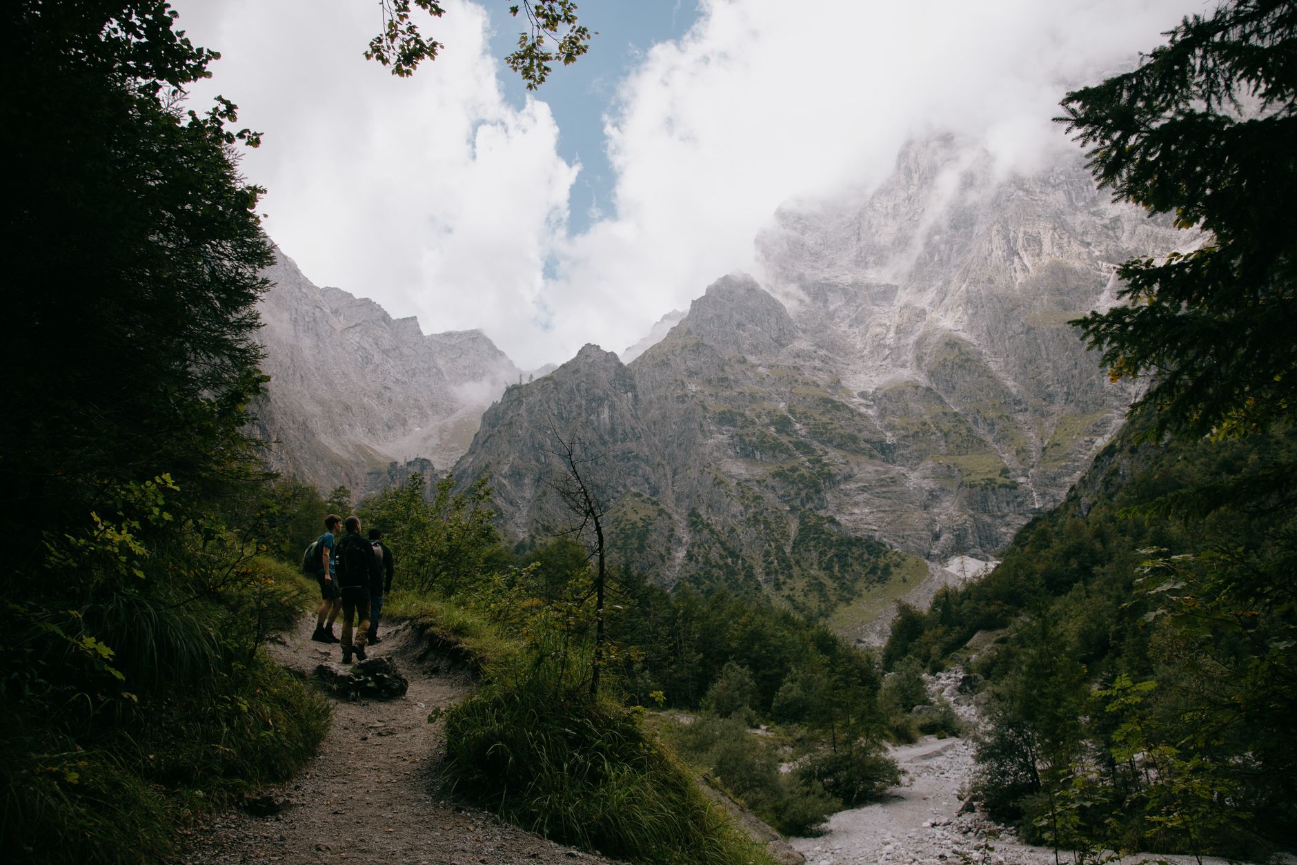 Narrow hiking trail winding through a steep mountain valley with terraced slopes