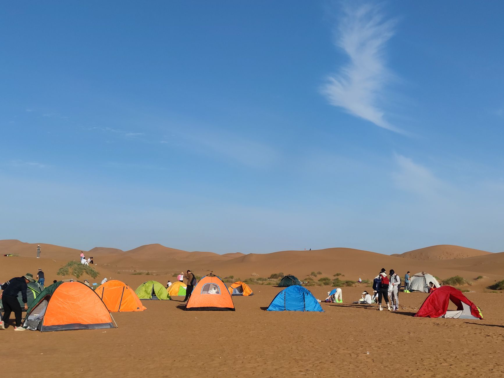 Traditional Bedouin tent camp set against dramatic rock cliffs in a desert landscape at dusk