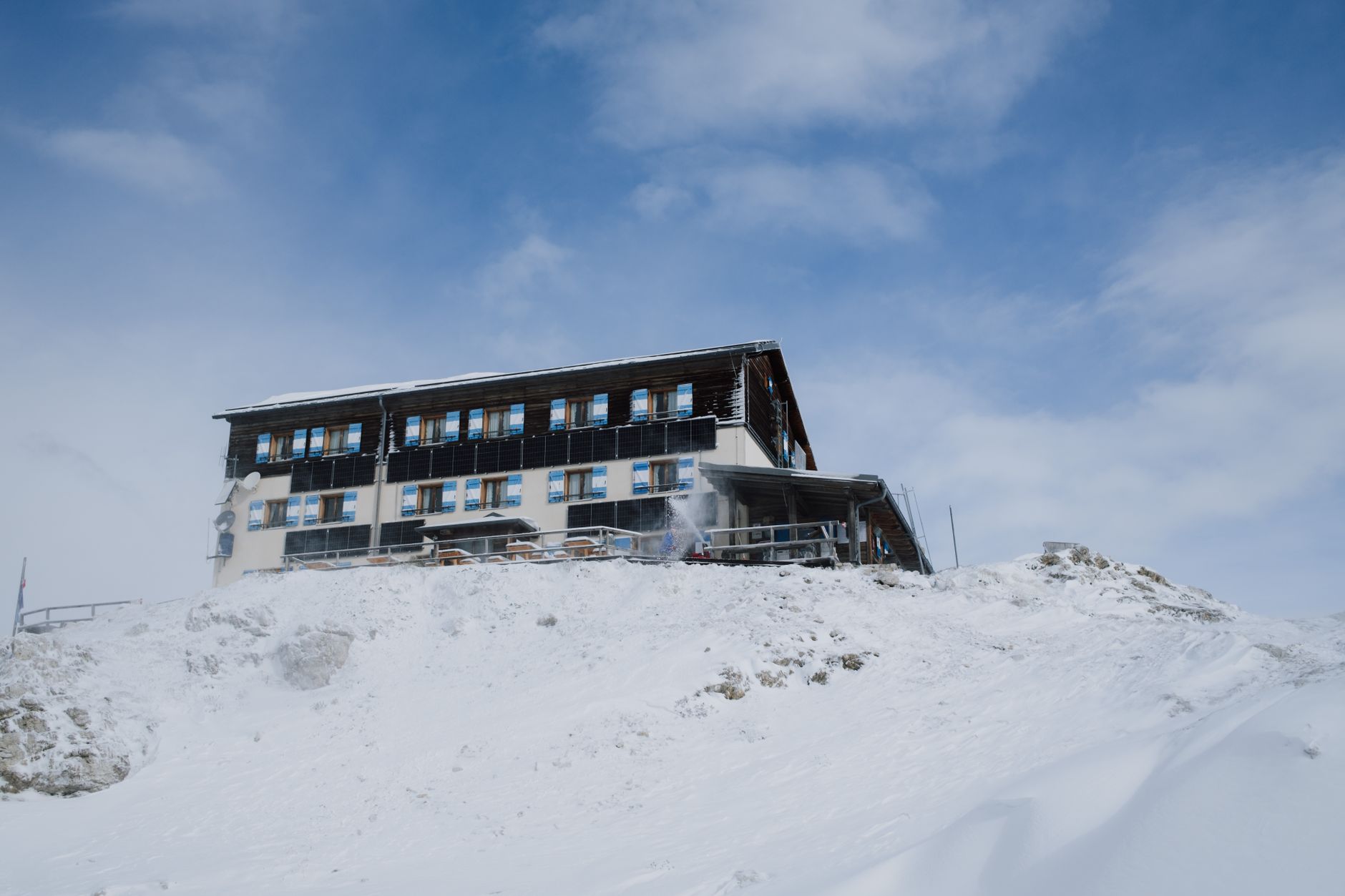 Small mountain lodge surrounded by deep snow in a remote high-altitude setting